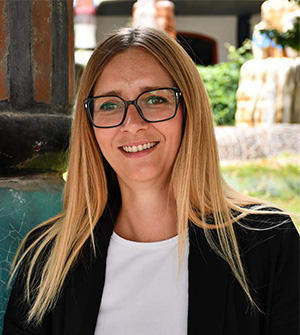 Frau mit Brille mit weißem Shirt und schwarzem Blazer.