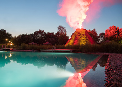 Pool mit künstlichem Vulkan der ausbricht im Abendlicht