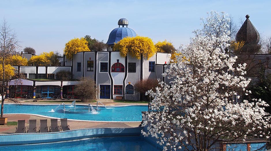 Thermalpool mit Hundertwasser Architektur im Hintergrund und Blüten